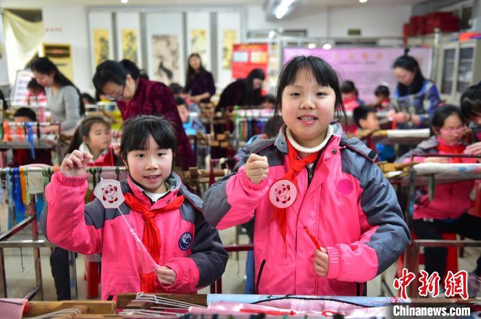 圖為小學(xué)生展示繡制好的2022年北京冬奧會吉祥物“冰墩墩”形象?！∮髟屏?攝