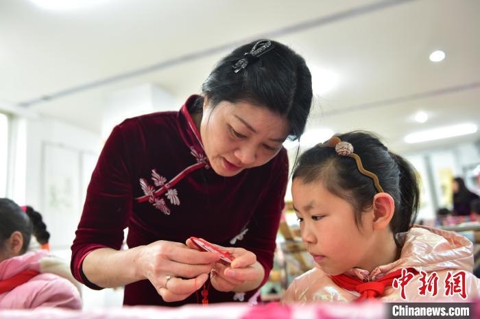 江西省級非遺豫章繡傳承人手把手指導(dǎo)小學(xué)生繡制2022年北京冬奧會吉祥物“冰墩墩”形象。　喻云亮 攝