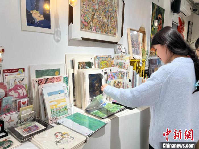 圖為藝術(shù)品商店內(nèi)，顧客挑選插畫作品?！＄婌?攝