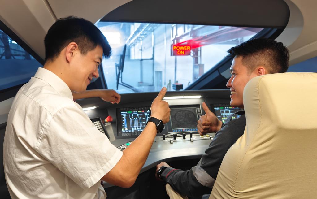 8月25日，在印度尼西亞萬隆的雅萬高鐵德卡魯爾動(dòng)車所內(nèi)，中國師傅穆振（左）在向印尼火車司機(jī)塞蒂亞萬講解動(dòng)車組出庫前的上電作業(yè)。