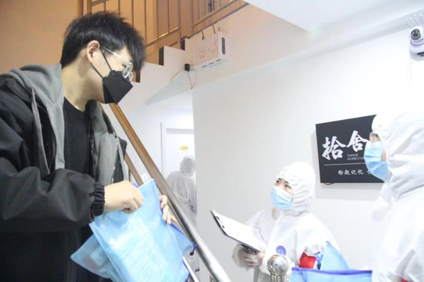 社區(qū)工作人員和志愿者身穿防護服上門送馬應龍大健康防疫包。徐帥攝