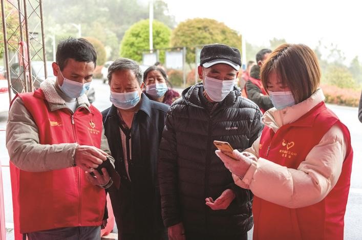 長(zhǎng)沙縣黨員志愿者正在幫助參與核酸檢測(cè)的群眾掃描“場(chǎng)所碼”。劉思源 攝