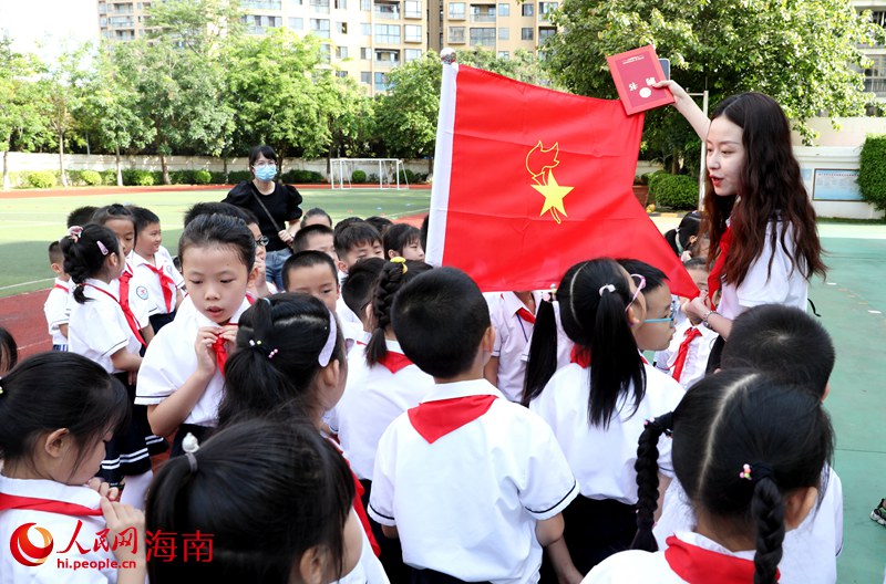 老師向少先隊(duì)員展示隊(duì)旗。人民網(wǎng) 符武平攝