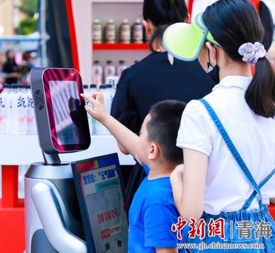 圖為一名小朋友正在和機(jī)器人“志愿者”進(jìn)行互動(dòng)。 沐聞 攝