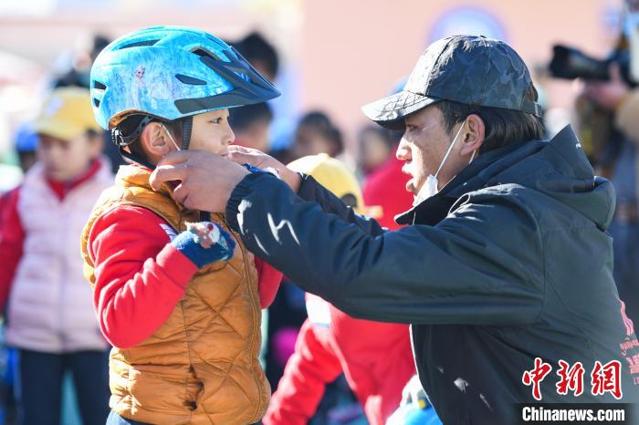 圖為拉薩市實(shí)驗(yàn)幼兒園孩子在教練的幫助下穿戴頭盔?！『闻罾?攝