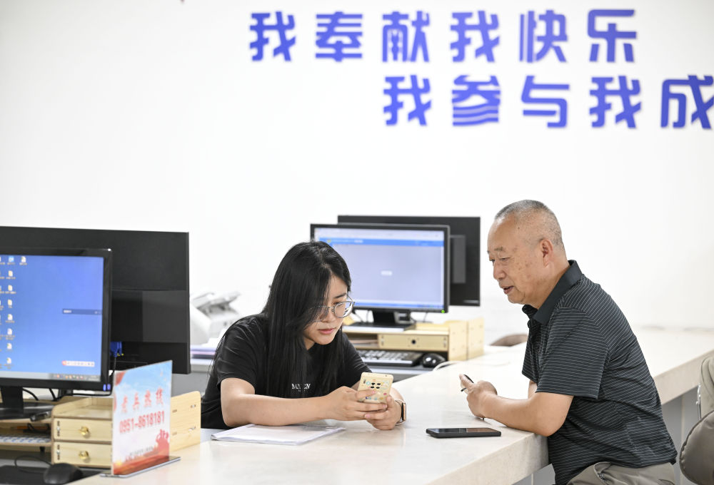 2024年6月20日，在寧夏銀川市金鳳區(qū)長城花園社區(qū)黨群服務(wù)中心，工作人員幫助居民辦理業(yè)務(wù)。圖片來源 新華社