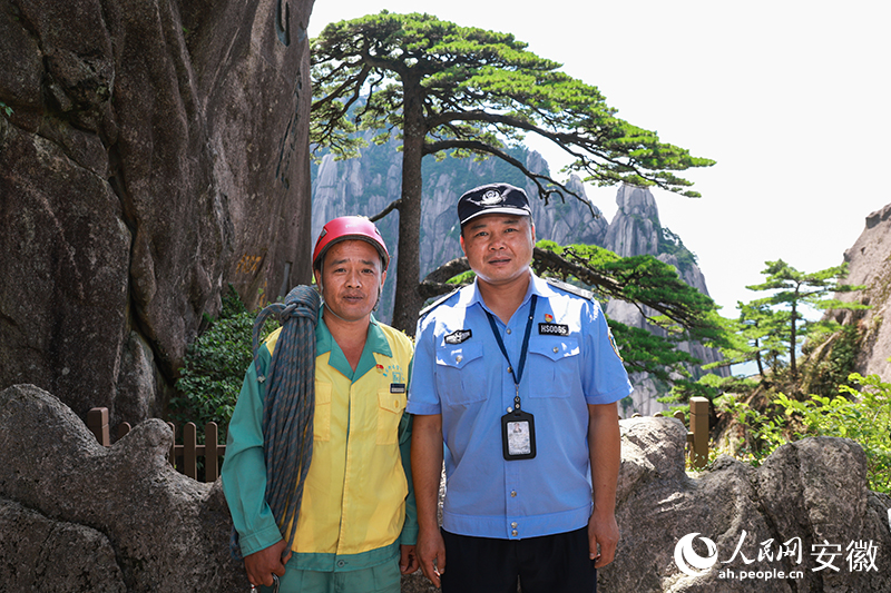 全國道德模范李培生（左）和胡曉春在迎客松前合影。人民網(wǎng)記者 張俊攝