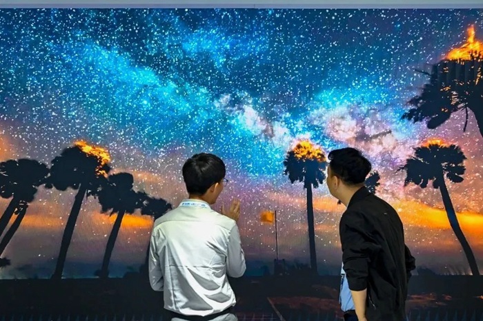 長春光博會希達(dá)電子展區(qū)，一位工作人員正在給一位觀眾講解。（長春新區(qū)供圖）
