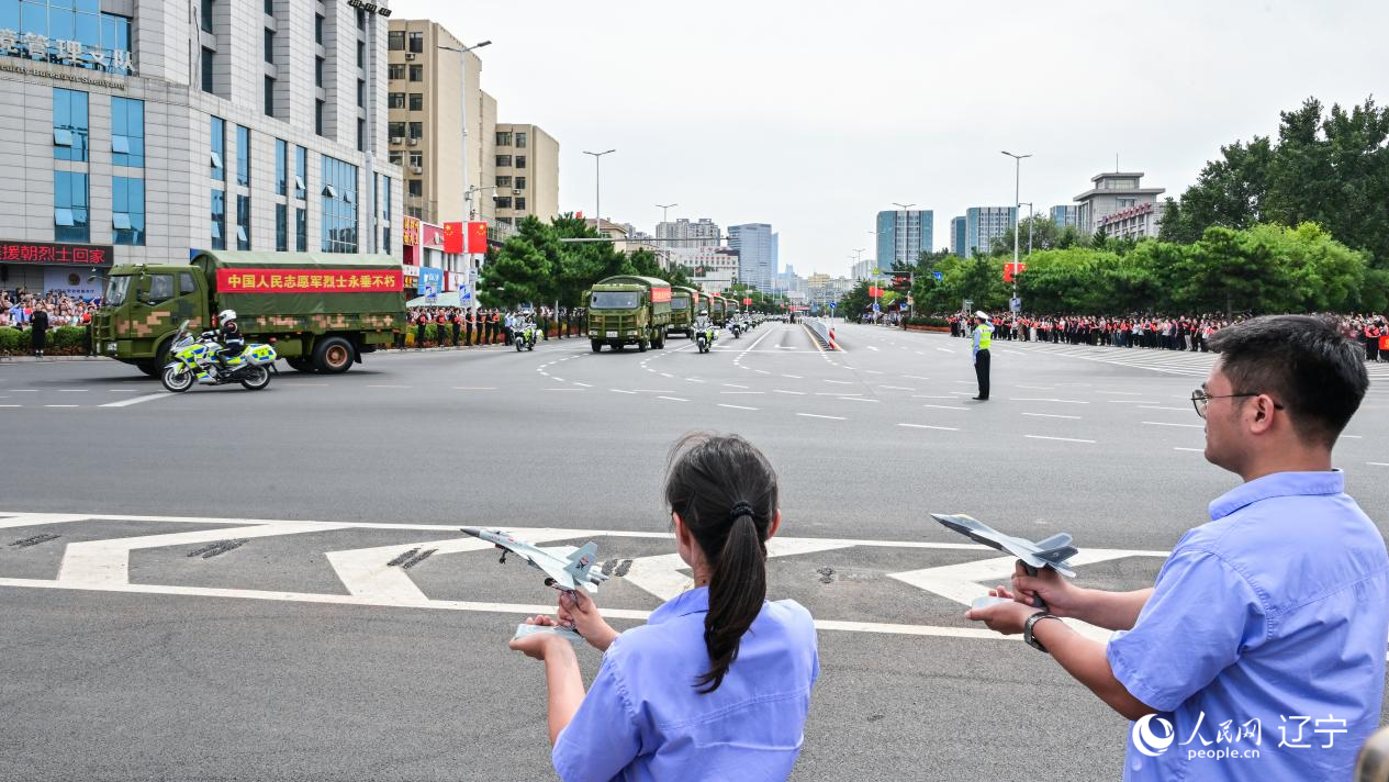 航空工業(yè)沈飛的青年技術(shù)人員拿著受閱戰(zhàn)機(jī)的模型迎接烈士遺骸。航空工業(yè)沈飛供圖
