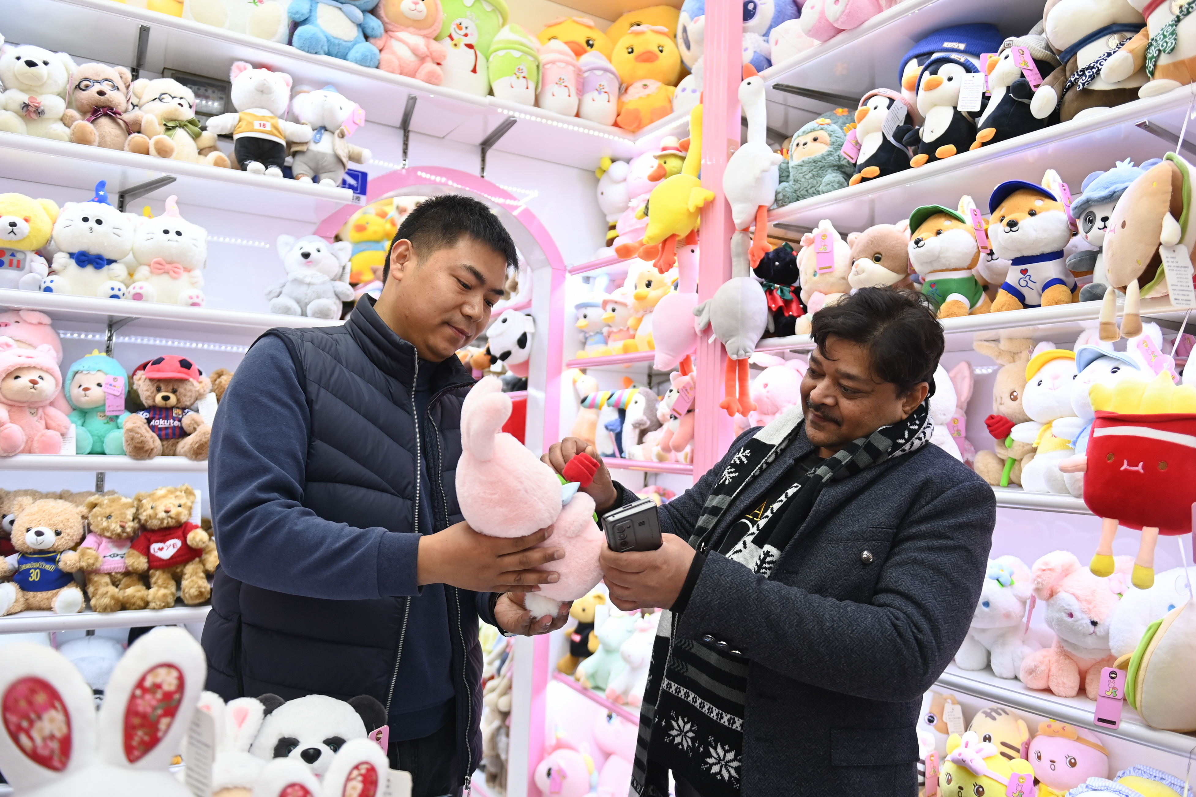 2023年2月2日，來自印度的客商（右）在義烏國際商貿城的一家玩具店鋪內選購。