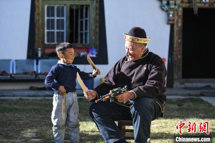 圖為米林縣扎西繞登鄉(xiāng)彩門村64歲的洛桑帶著孫子巴桑在院子的草地上玩耍。　何蓬磊 攝
