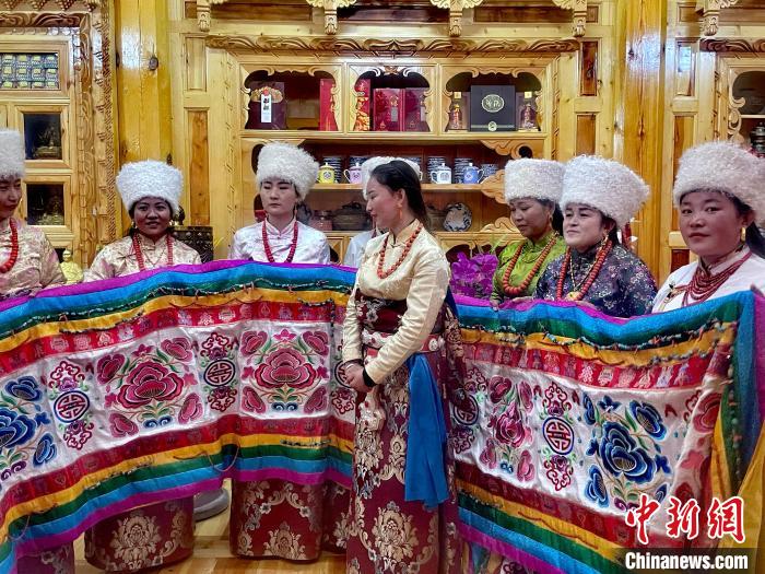 圖為女性展示村民自發(fā)繡制的“百米五彩哈達(dá)”?！±钣穹?攝