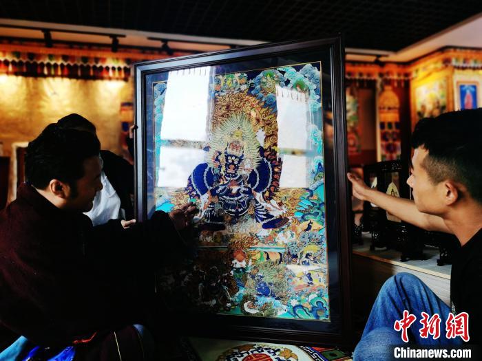 圖為久美尖措(左)與徒弟們展示唐卡作品?！?zhí)砀?攝