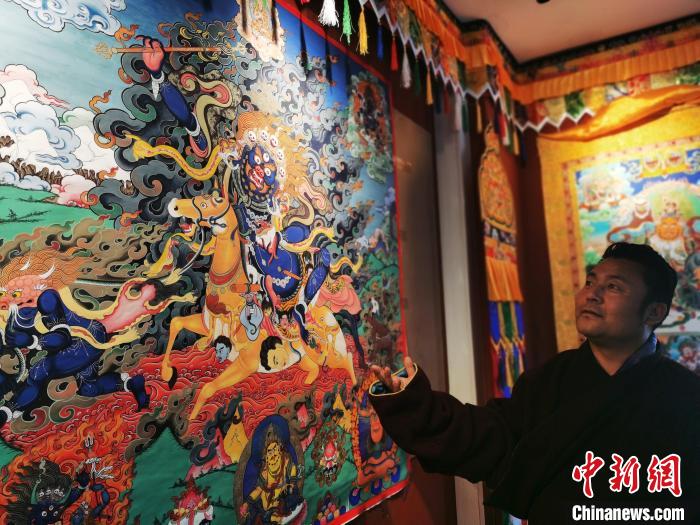 圖為久美尖措展示唐卡作品?！?zhí)砀?攝