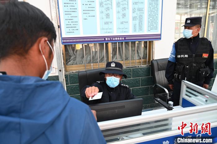 圖為移民管理警察登記完身份信息后將證件歸還給行人?！≮w朗 攝