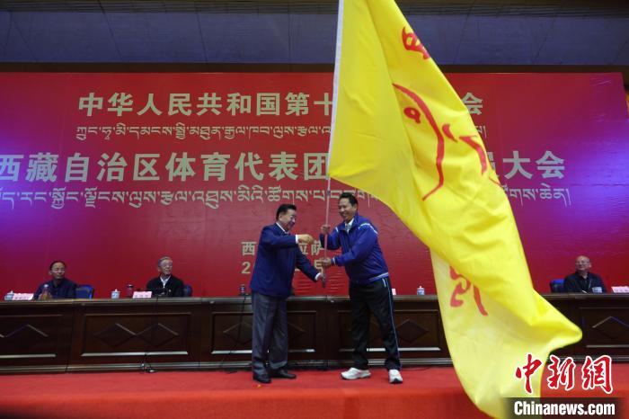 西藏自治區(qū)副主席甲熱·洛桑丹增授代表團團旗，西藏自治區(qū)體育局局長尼瑪次仁接旗。　冉文娟 攝