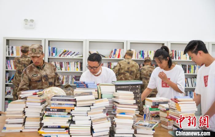 圖為志愿者們和邊防戰(zhàn)士整理圖書?！詵| 攝