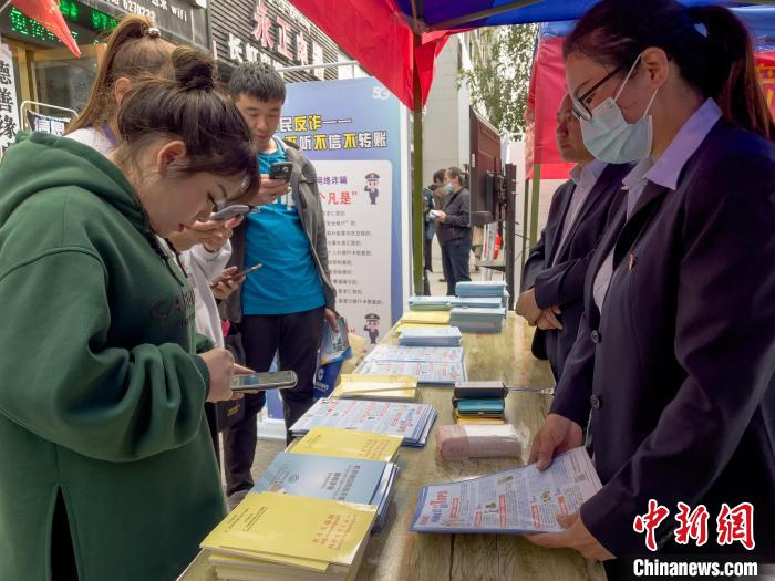圖為工作人員正在向路過(guò)市民介紹國(guó)家反詐中心軟件的功能?！≈x牧 攝