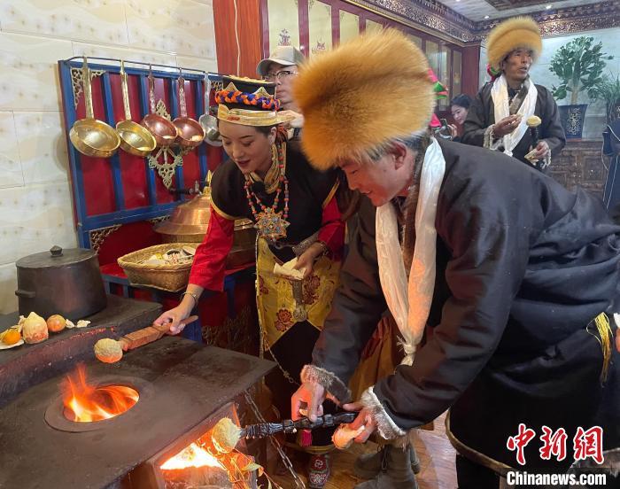 圖為人們在火上烤節(jié)日美食“結(jié)達”?！∪轿木?攝
