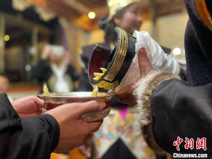圖為主人在碗中斟滿青稞酒?！∪轿木?攝