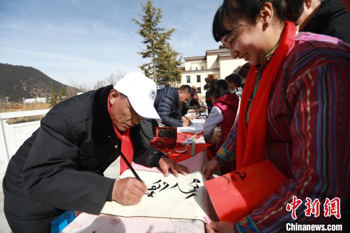 圖為林芝市文聯(lián)書法家協(xié)會(huì)會(huì)員向民眾贈(zèng)送藏文書法作品?！埩?攝