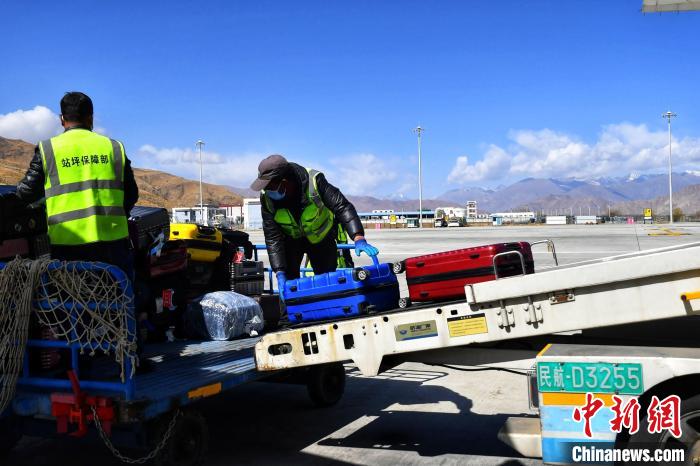 圖為機場工作人員傳送旅客行李箱。　周航 攝