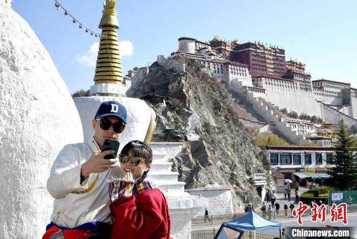 4月17日，游客身著藏式元素服裝在拉薩布達拉宮觀景臺拍照留念?！±盍?攝