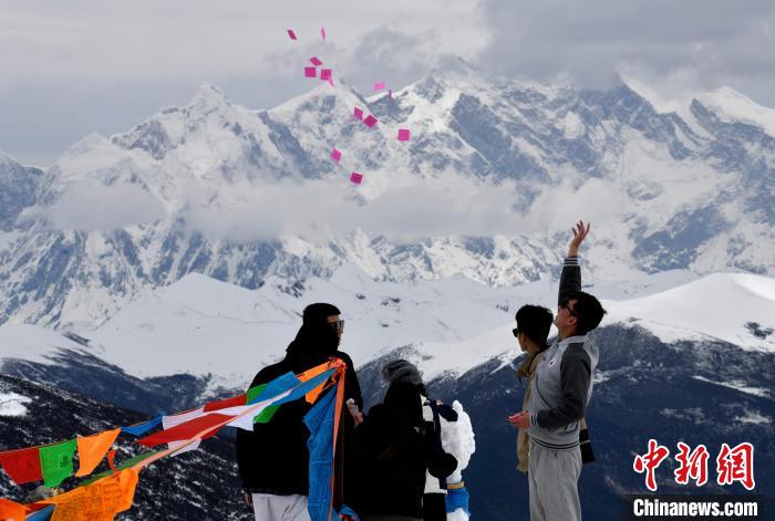 圖為5月14日，游客在西藏林芝色季拉山觀景臺(tái)拋灑“隆達(dá)”(風(fēng)馬旗，藏族民眾的一種祈福方式)?！±盍?攝